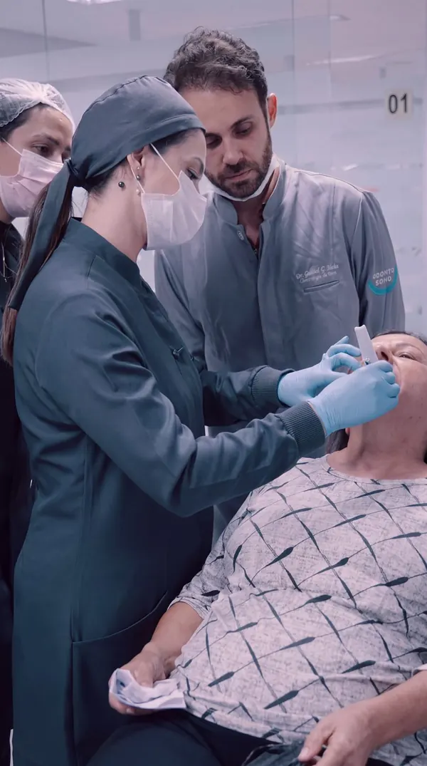 Dra. Thays Crosara e equipe avaliando a paciente na cadeira odontológica